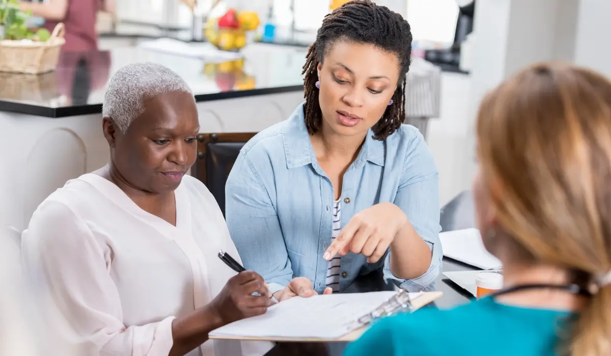 Older woman and her adult daughter meeting with an insurance advisor to review final expense insurance paperwork