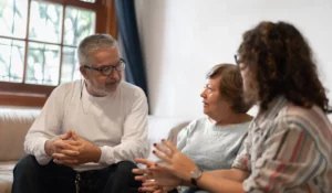 Senior man and woman in discussion with adult daughter about end-of-life planning in a calm home setting.