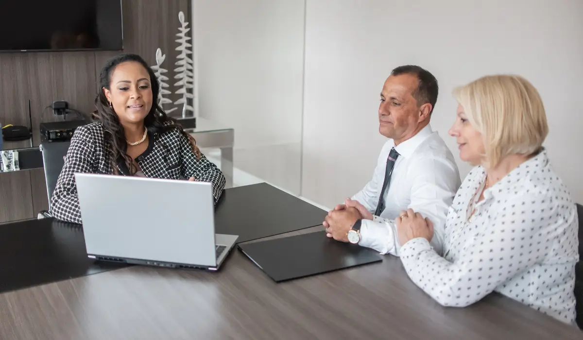 Senior couple discussing traditional life VS final expense insurance options with a professional advisor at a modern office table.