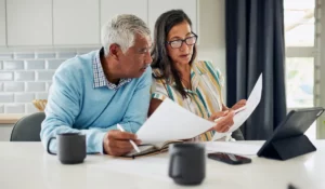 Funeral Costs paperwork beside senior couple preparing future family financial decisions and insurance coverage planning carefully.